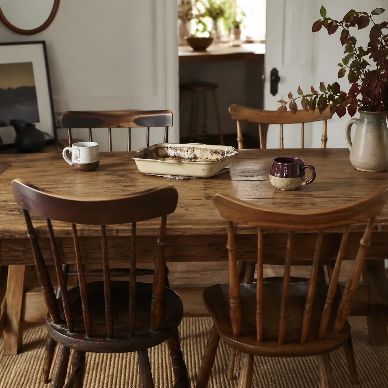 Des chaises dépareillées autour d’une table avec des tasses et un plat.